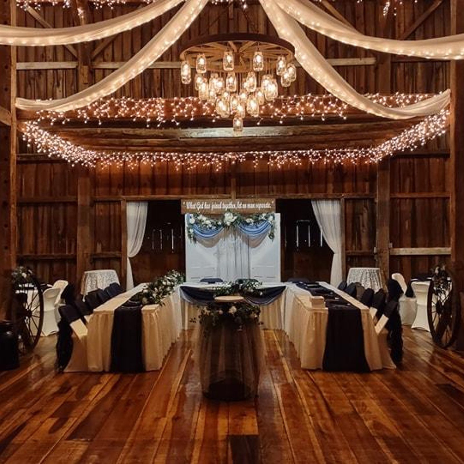 Fairman Family Farms barn head table with chandelier and string lights